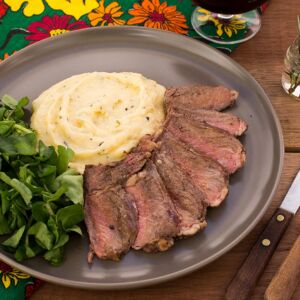 Bife ancho, aligot de macaxeira com wasabi e cebolas caramelizadas