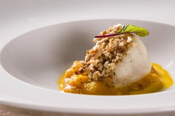 Peixe em crosta de castanha, purê de abóbora e molho de champagne